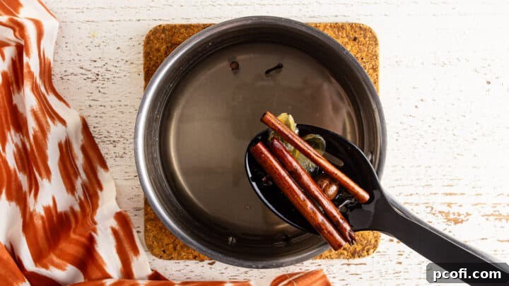 Straining whole spices out of homemade pumpkin spice syrup.
