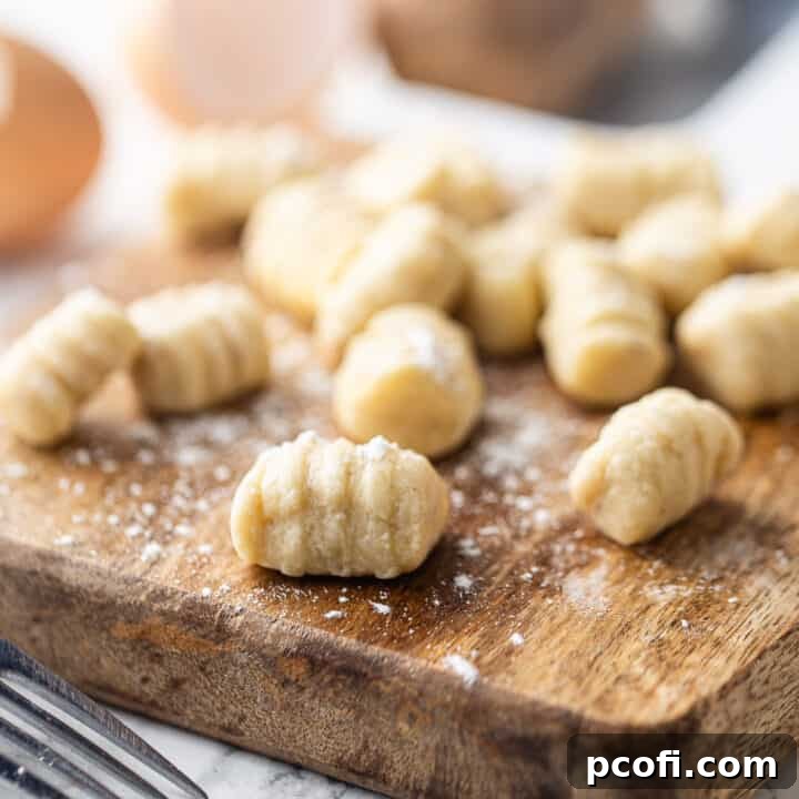 Homemade gnocchi on a wooden board with a sprinkling of flour, ready to be cooked. Learn how to make light and pillowy potato gnocchi with our comprehensive guide.