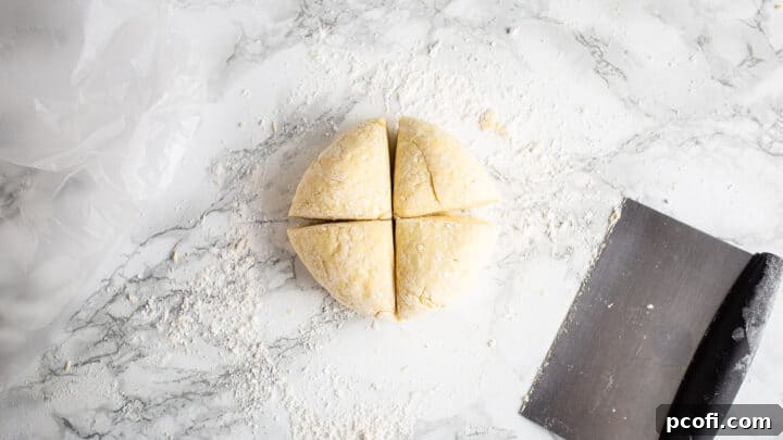 Dividing a ball of gnocchi dough into four equal portions using a bench scraper, an organized step before shaping.