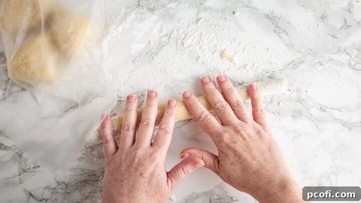 Expertly rolling gnocchi dough into long, even ropes on a floured wooden surface, a crucial step for uniform dumplings.