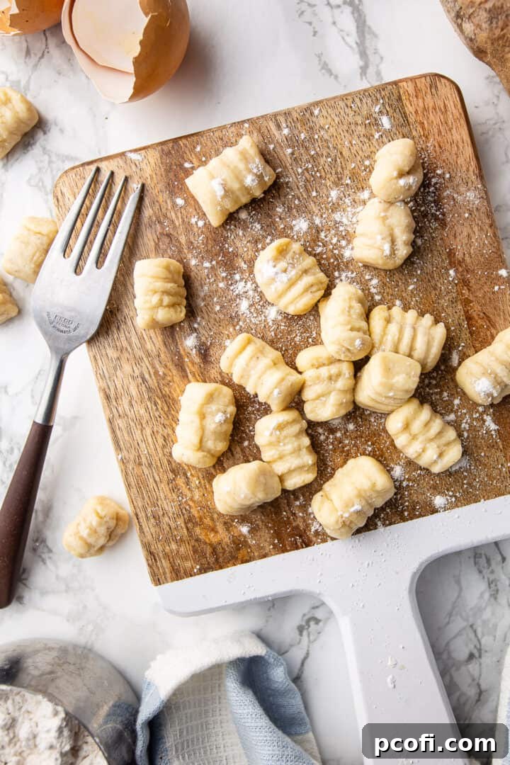 A perfectly plated dish of potato gnocchi, shaped with a fork, generously coated in aromatic sage brown butter and sprinkled with Parmesan cheese.