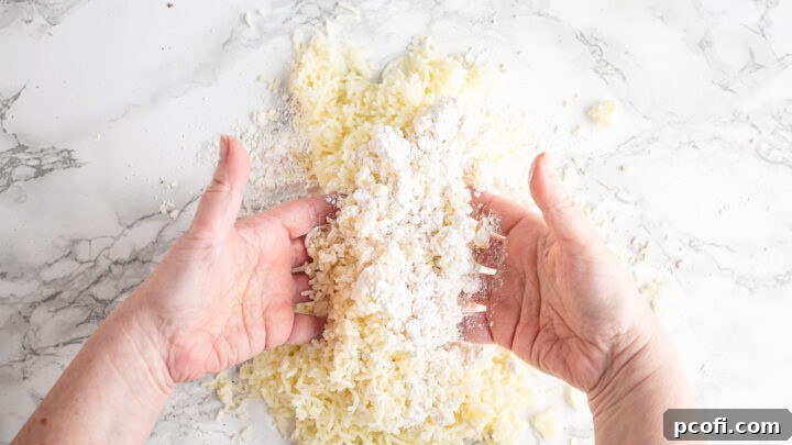 Gently tossing riced potatoes with flour on a wooden surface, ensuring every potato strand is coated for a perfect gnocchi dough.