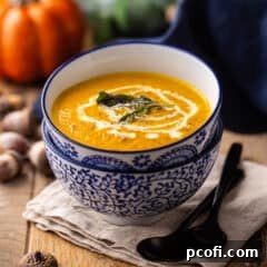 Pumpkin soup with sage and cream, served in a blue and white bowl.