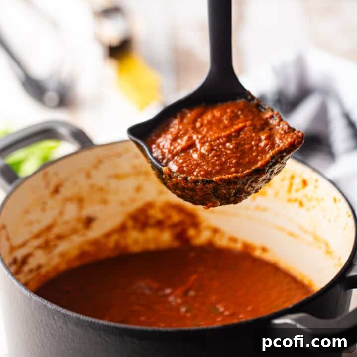 Freshly made tomato sauce being ladled from a large enameled cast iron Dutch oven.