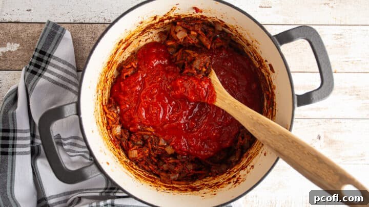 Adding crushed tomatoes to make tomato sauce.