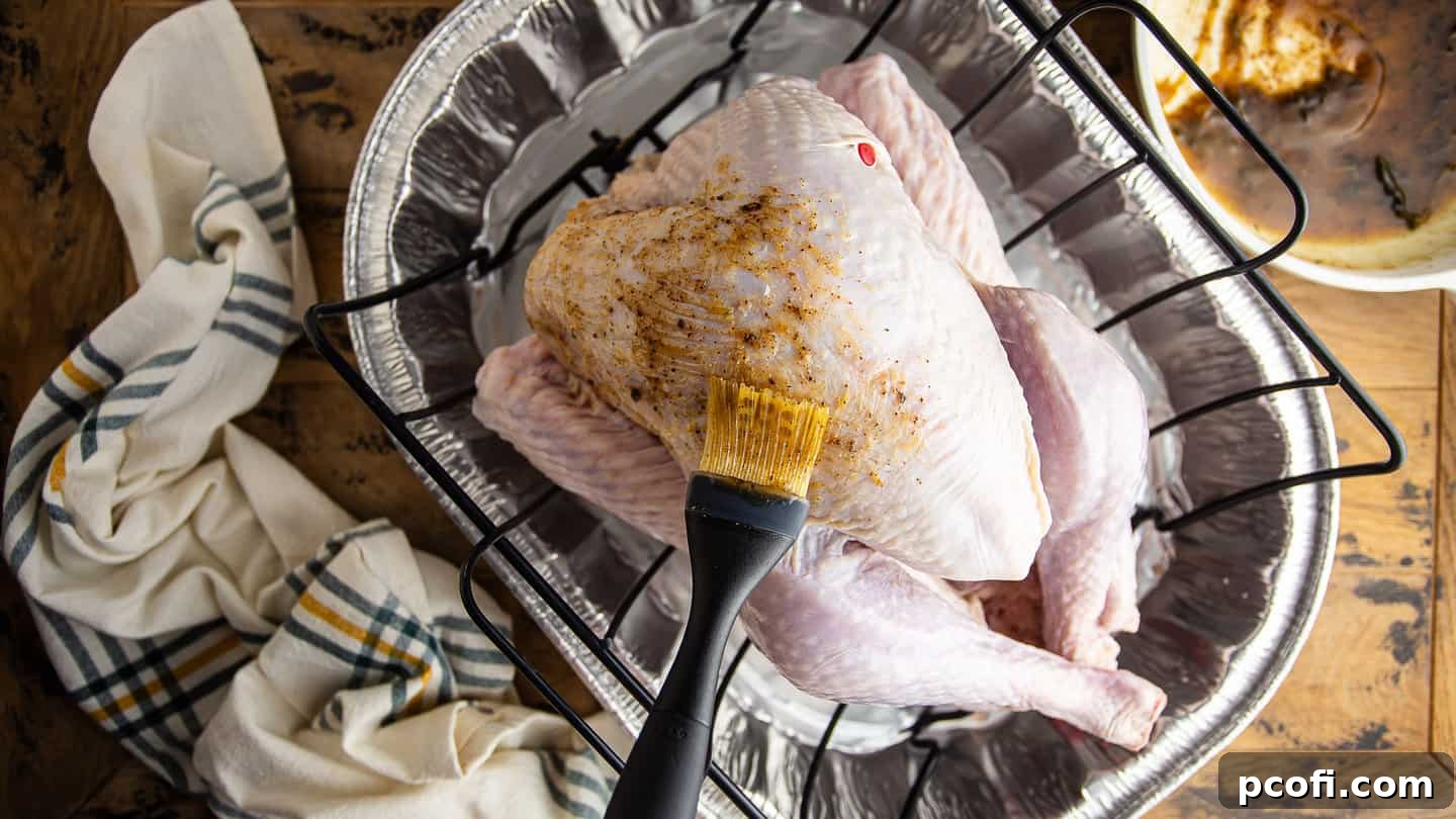 Brushing an uncooked turkey with maple and sage brown butter glaze.