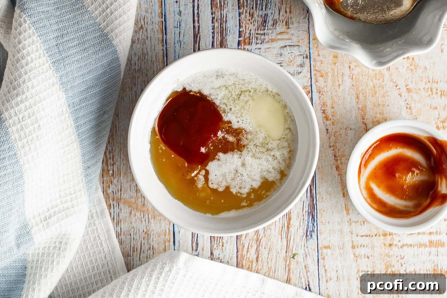 Melted butter, orange marmalade and sriracha sauce in a small bowl, ready to be mixed.