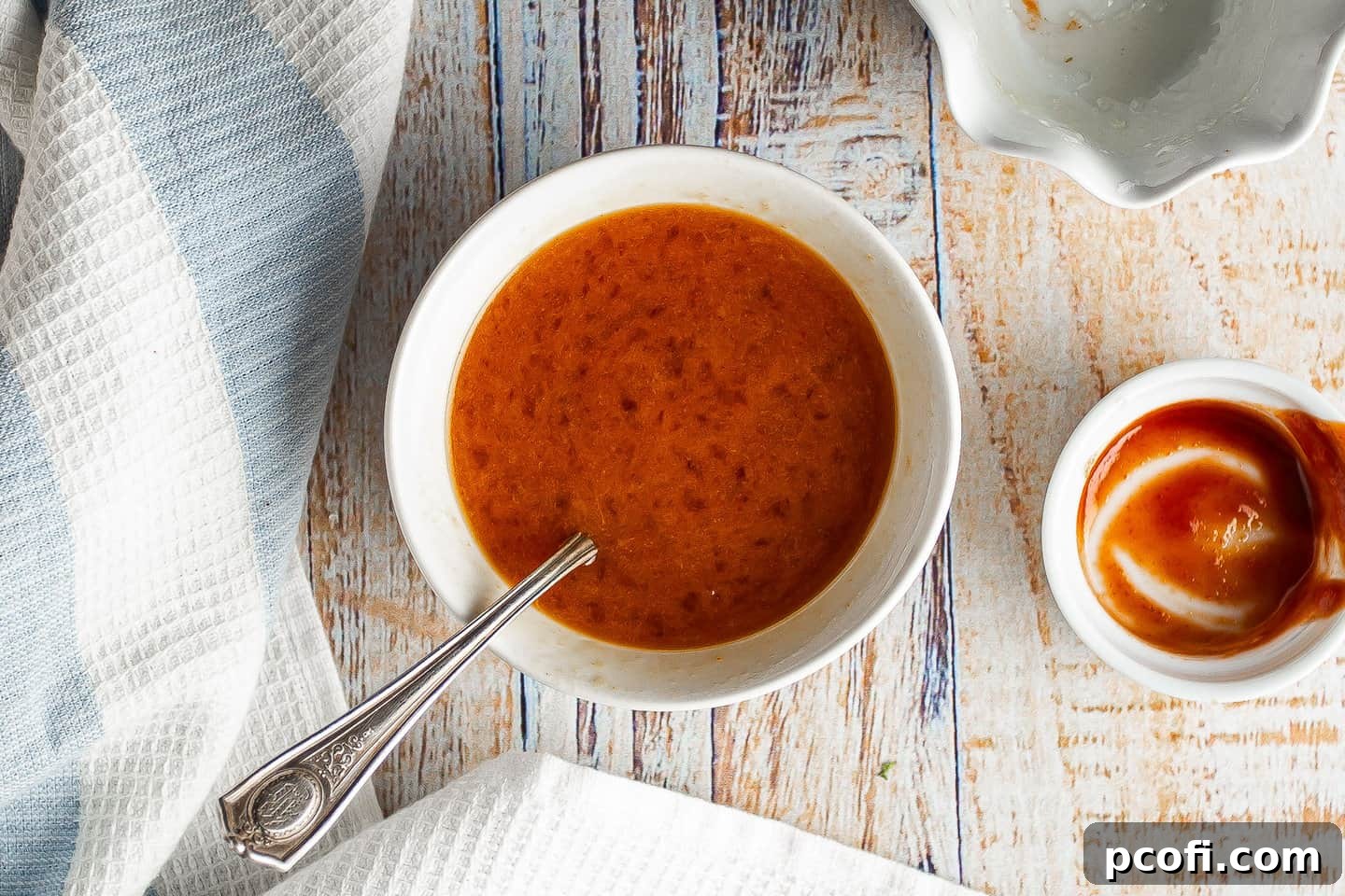 Orange Sriracha glaze in a small white bowl, perfectly mixed.