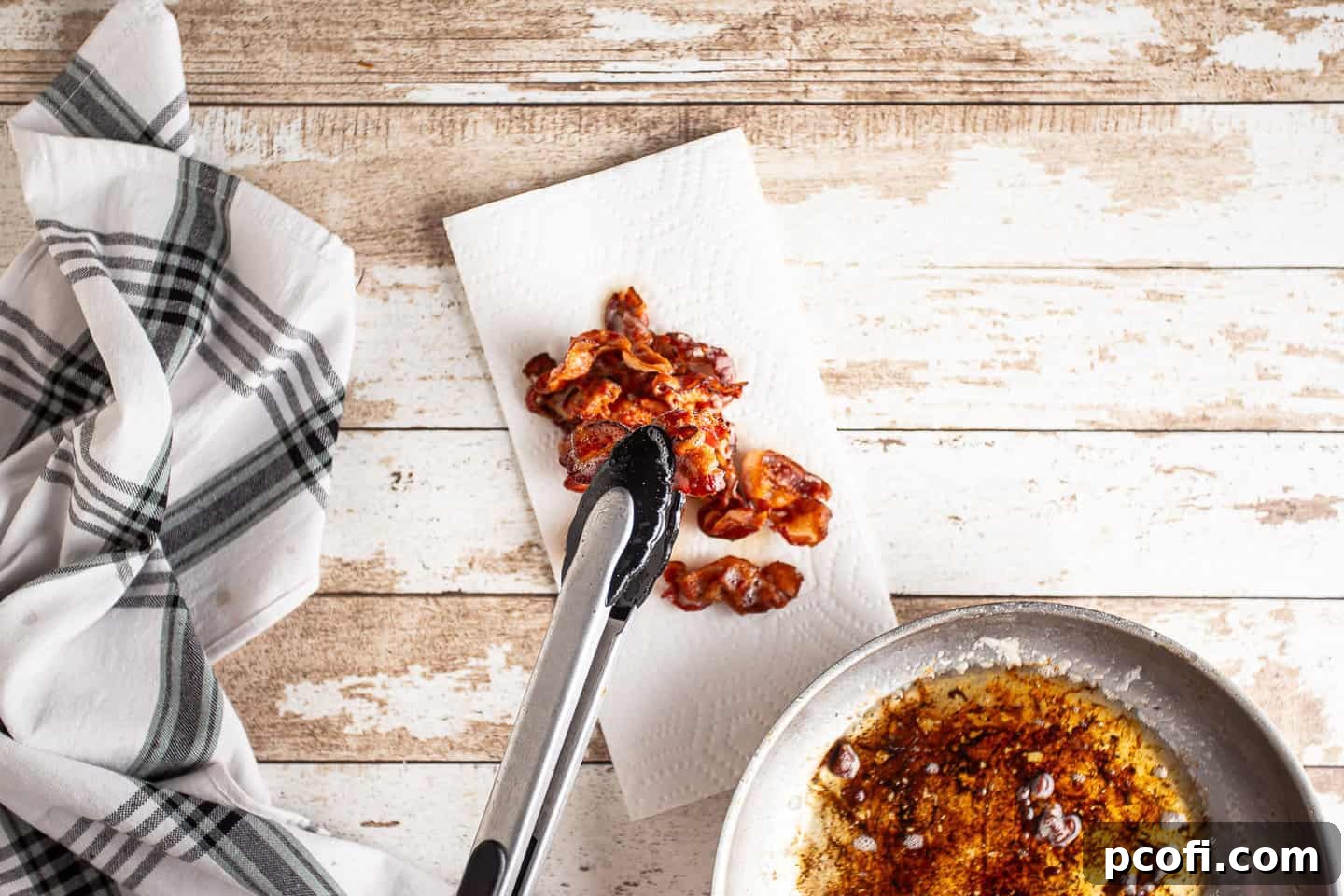 Removing perfectly cooked crispy bacon from the hot pan and placing it on paper towels to drain, leaving rendered fat behind.