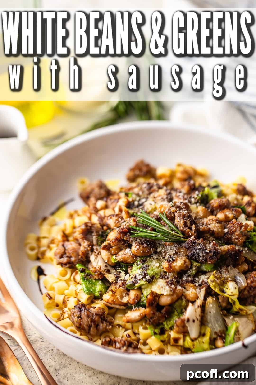 Close-up of white beans and greens with sausage, ditalini pasta, a drizzle of balsamic glaze, fresh rosemary, and grated Parmigiano Reggiano cheese.