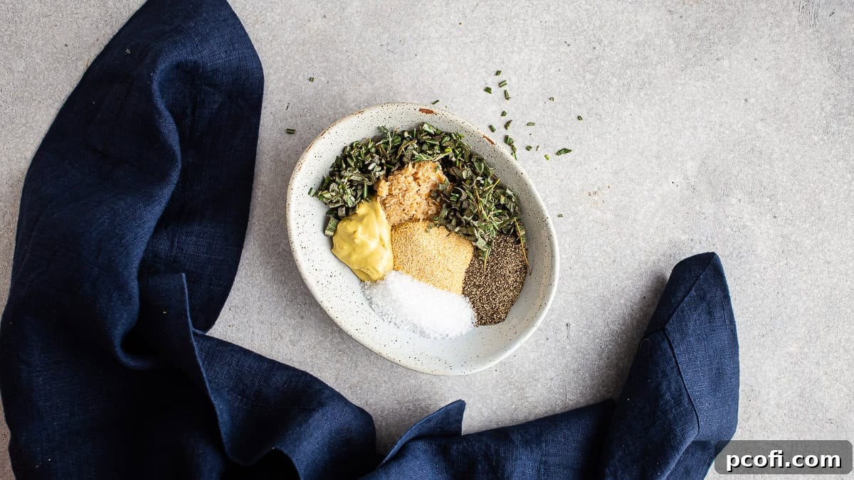 Individual ingredients for the herbed compound butter, including fresh herbs, garlic powder, and Dijon mustard, are placed in a bowl, ready to be mixed.