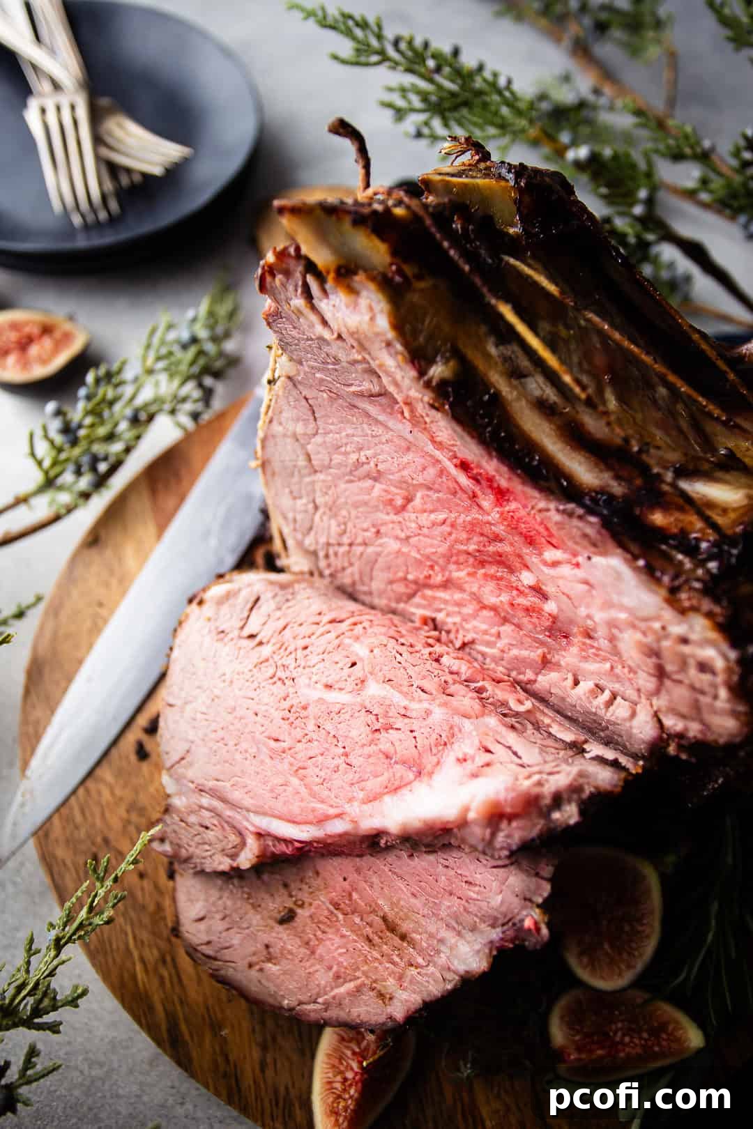 A glorious standing rib roast, expertly carved into thick, succulent slices, resting on a sturdy wooden cutting board, ready to be served.