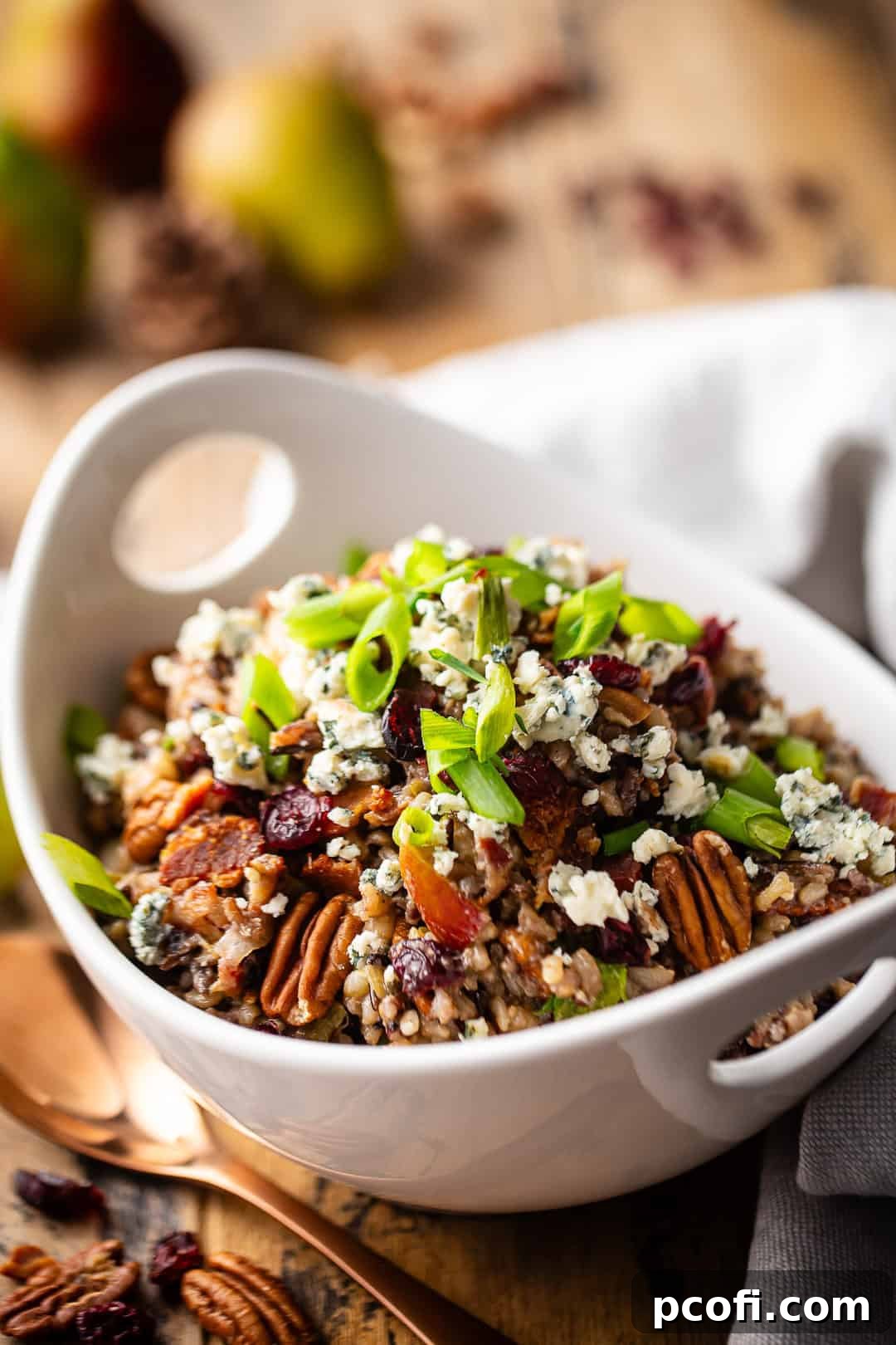 A large bowl of wild rice stuffing with fresh green onions and toasted pecans on top, ready to serve for a holiday feast.