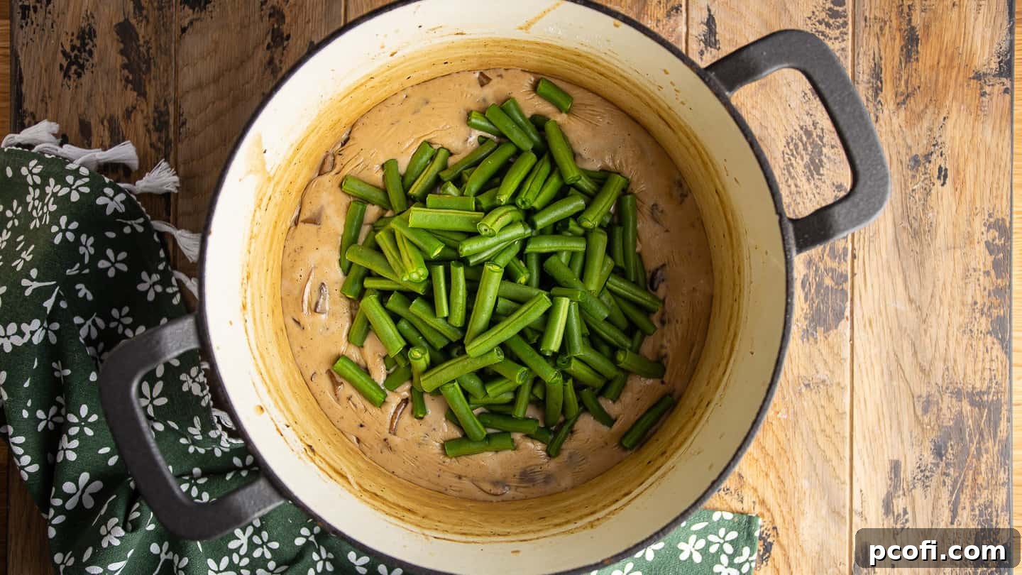 Adding fresh green beans to a creamy mushroom sauce.