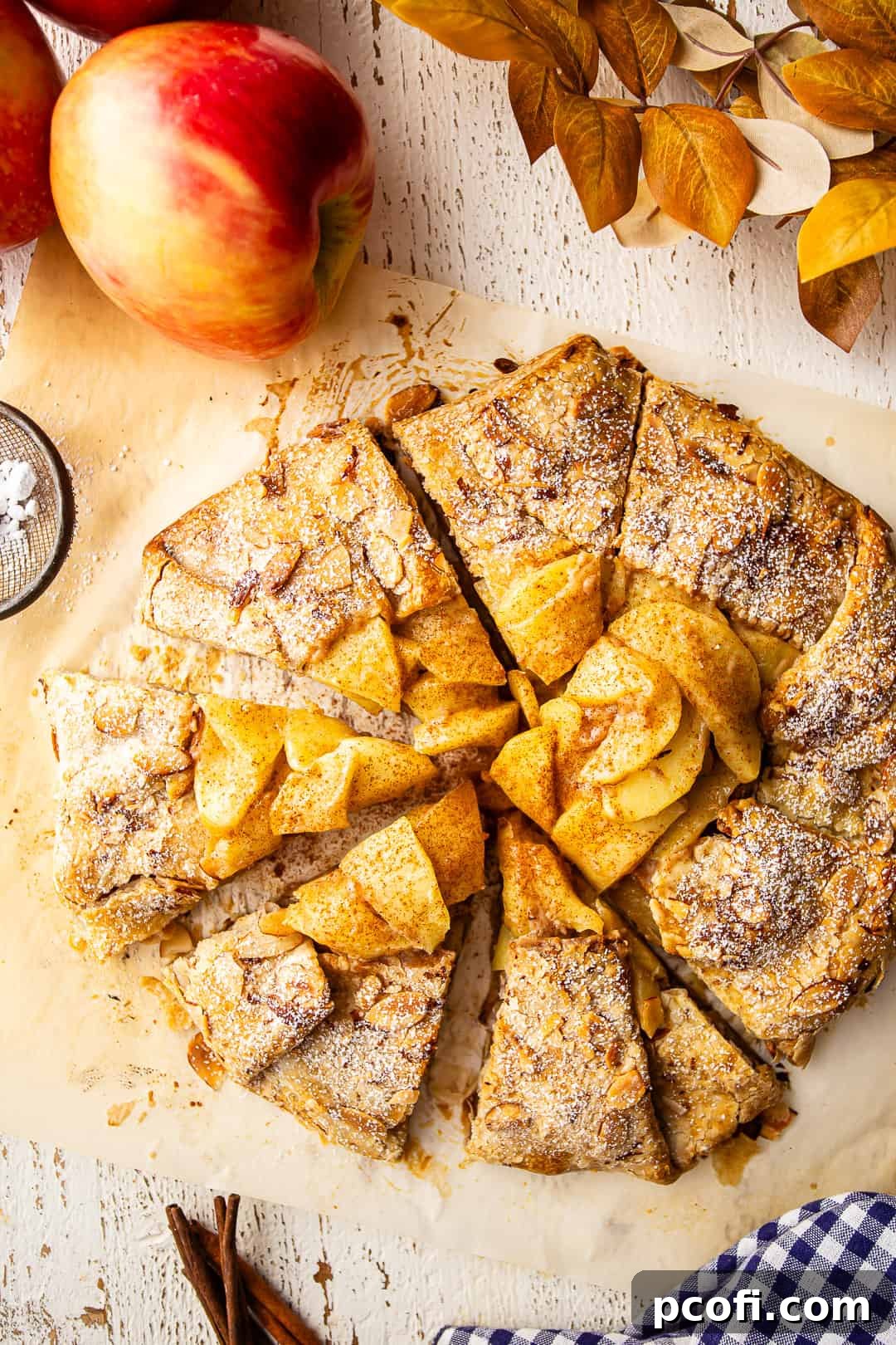 A baked apple galette, sliced into generous portions and elegantly presented on a distressed white board, ready to be enjoyed.