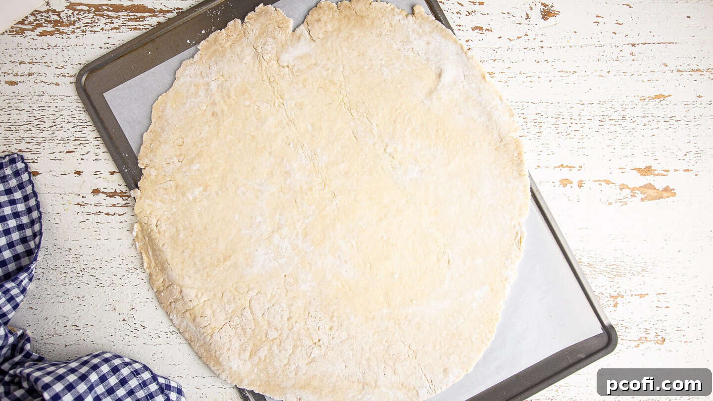 Apple galette pastry dough, rolled out into a large circle and placed on a baking sheet, ready for filling.