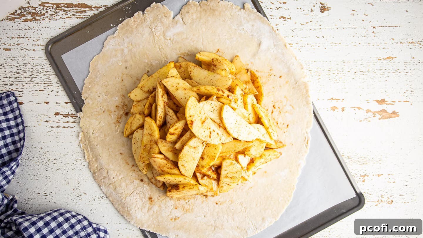 Apple galette filling piled high in the middle of the pastry dough, leaving a wide border.