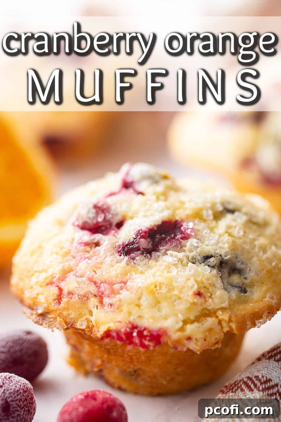 Freshly baked orange cranberry muffins artfully arranged with vibrant oranges and ruby-red cranberries in the background, ready to be enjoyed.