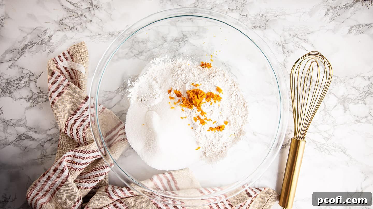 All dry ingredients for cranberry orange muffins neatly placed in a large glass mixing bowl, ready for combining.