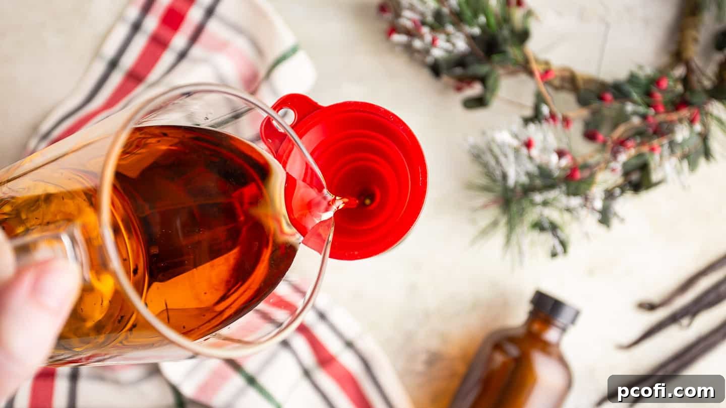 Pouring rich amber bourbon whiskey into a glass bottle containing split vanilla beans, utilizing a small silicone funnel to ensure a clean and spill-free transfer.