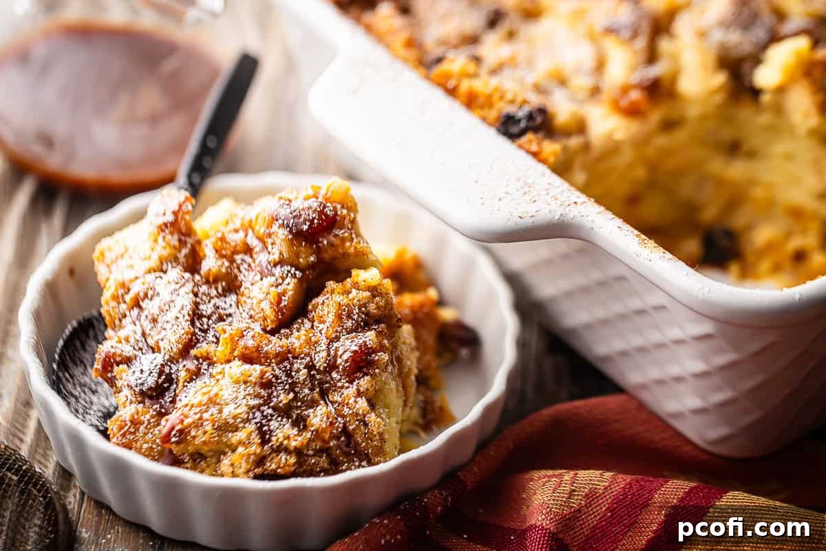 Baked bread pudding in a white dish with the pan of bread pudding in the background.