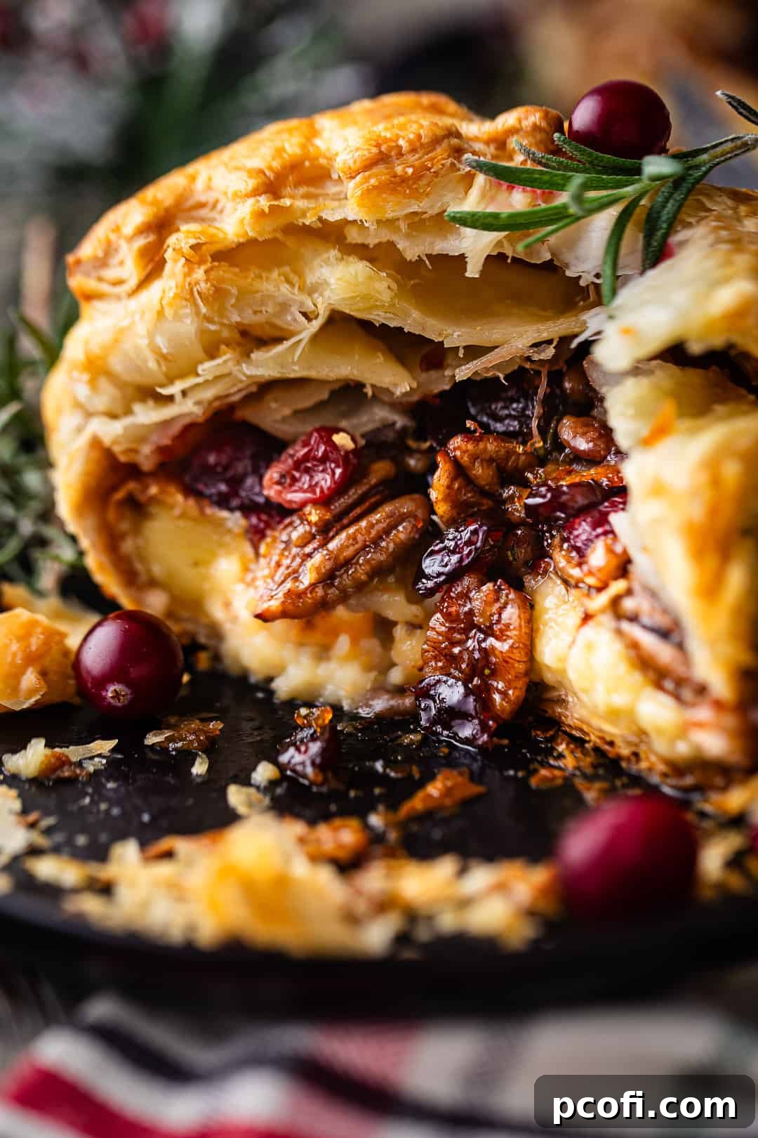 A baked brie recipe, artfully cut open to reveal the irresistibly oozy, molten filling of cheese, cranberries, and pecans.