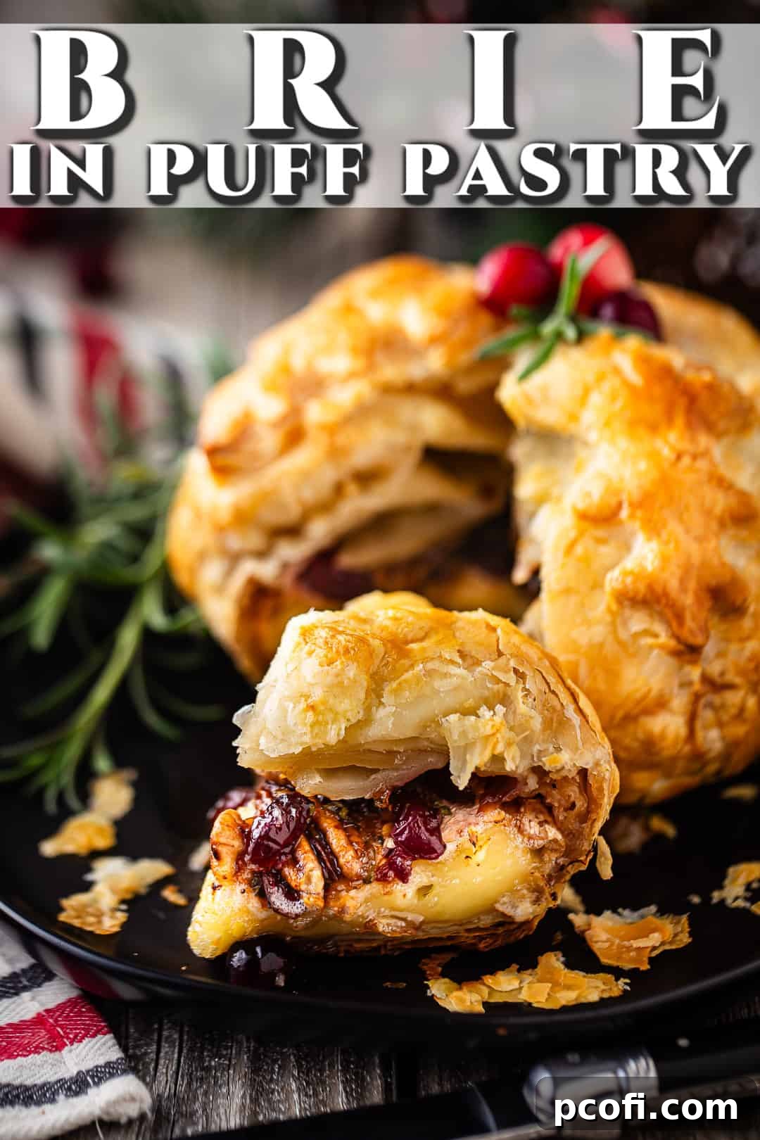 Baked brie with cranberries and pecans on a dark plate, garnished with fresh rosemary sprigs, ready for serving.