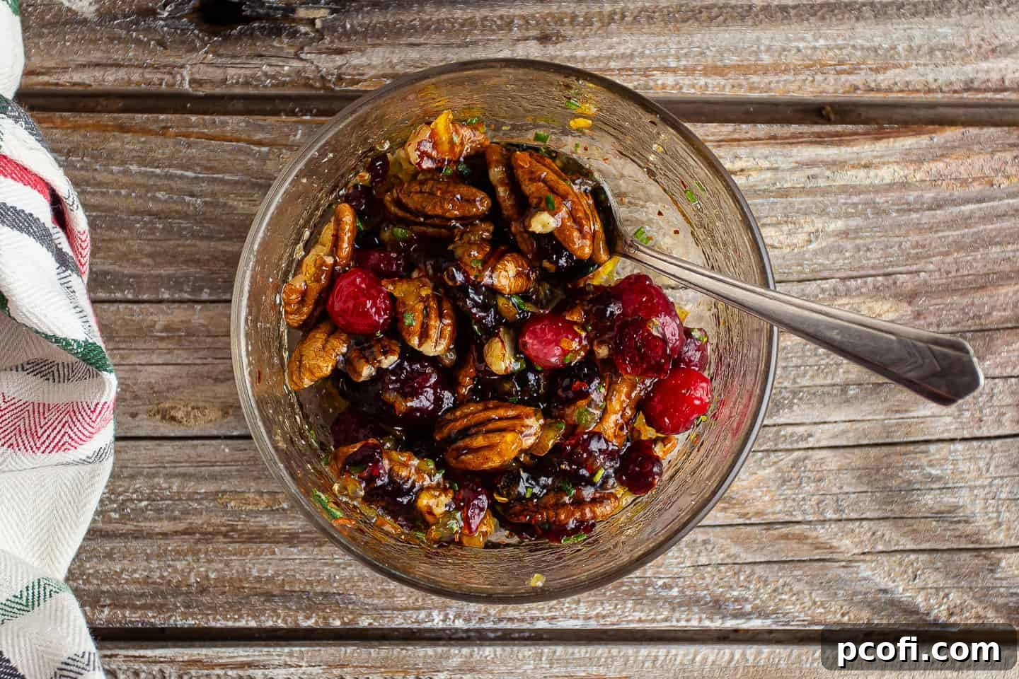 The fully mixed jam topping for baked brie, rich with cranberries, pecans, and orange, in a small glass bowl.