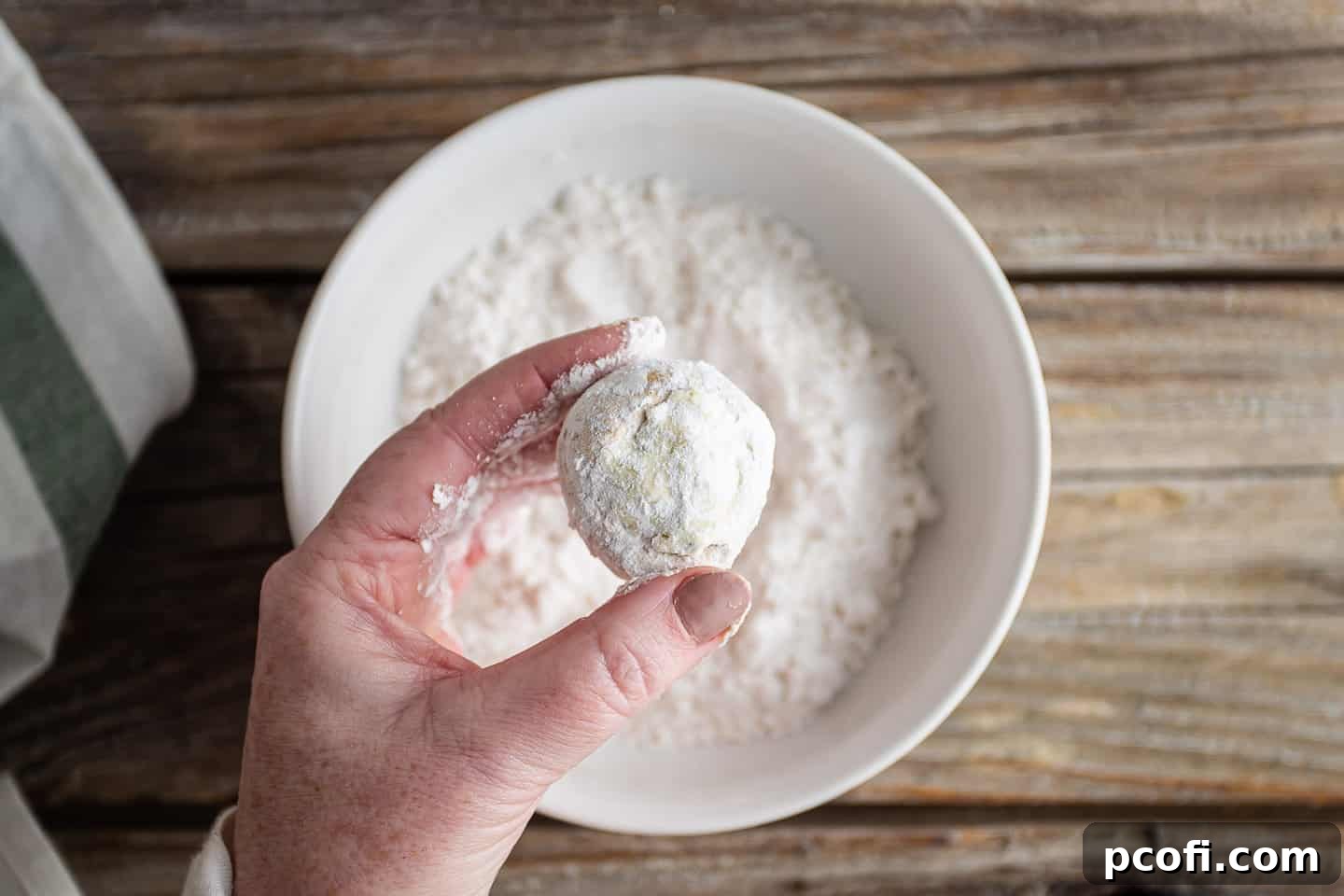 Dredging stuffed mushrooms with flour.