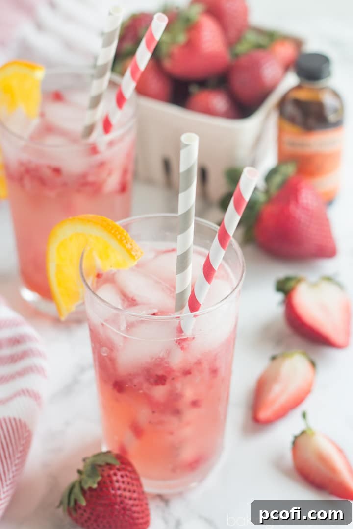 A close-up of the refreshing Strawberry Orange Blossom Sparkler, showing ice cubes and fruit pieces.
