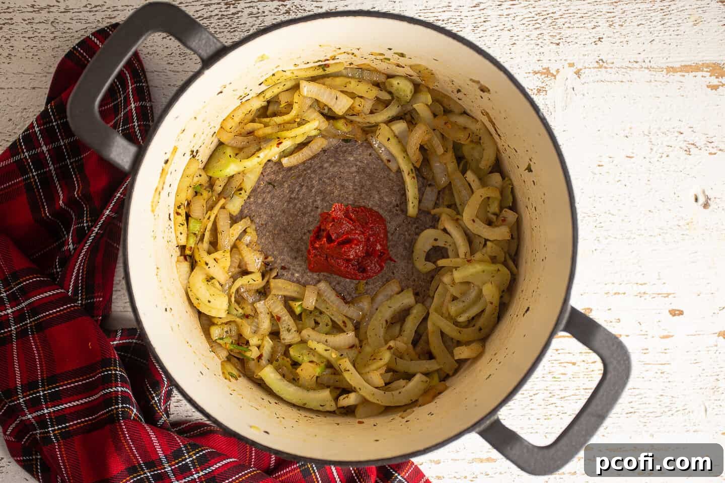 Adding tomato paste to vegetables and seasonings.