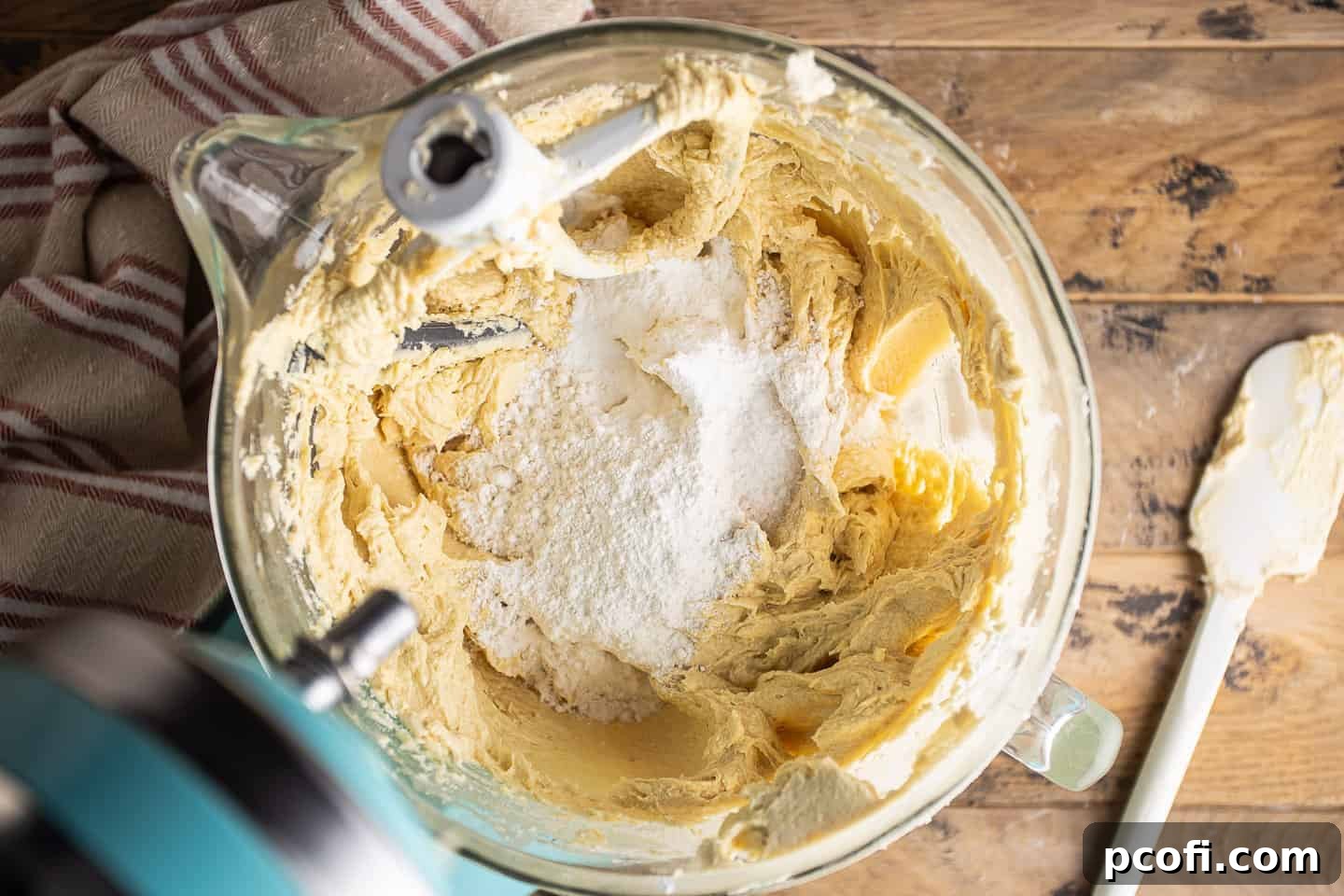 Mixing dry ingredients such as flour, baking powder, and salt into the rum cake batter.