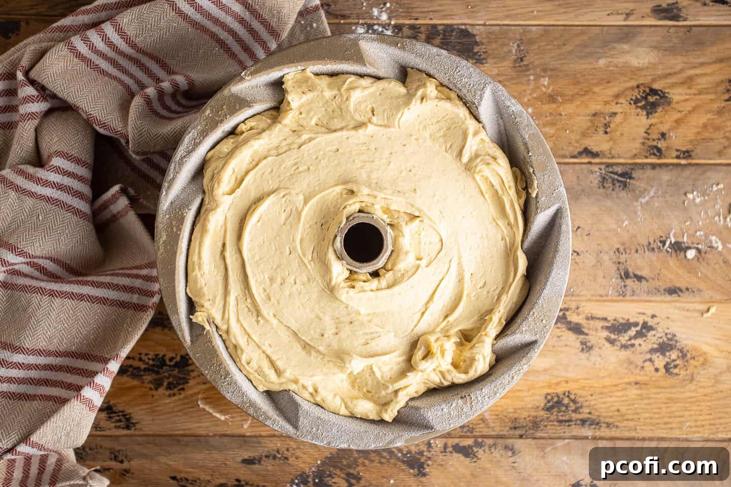 Unbaked rum cake batter nestled in a spiral bundt pan, ready for the oven.