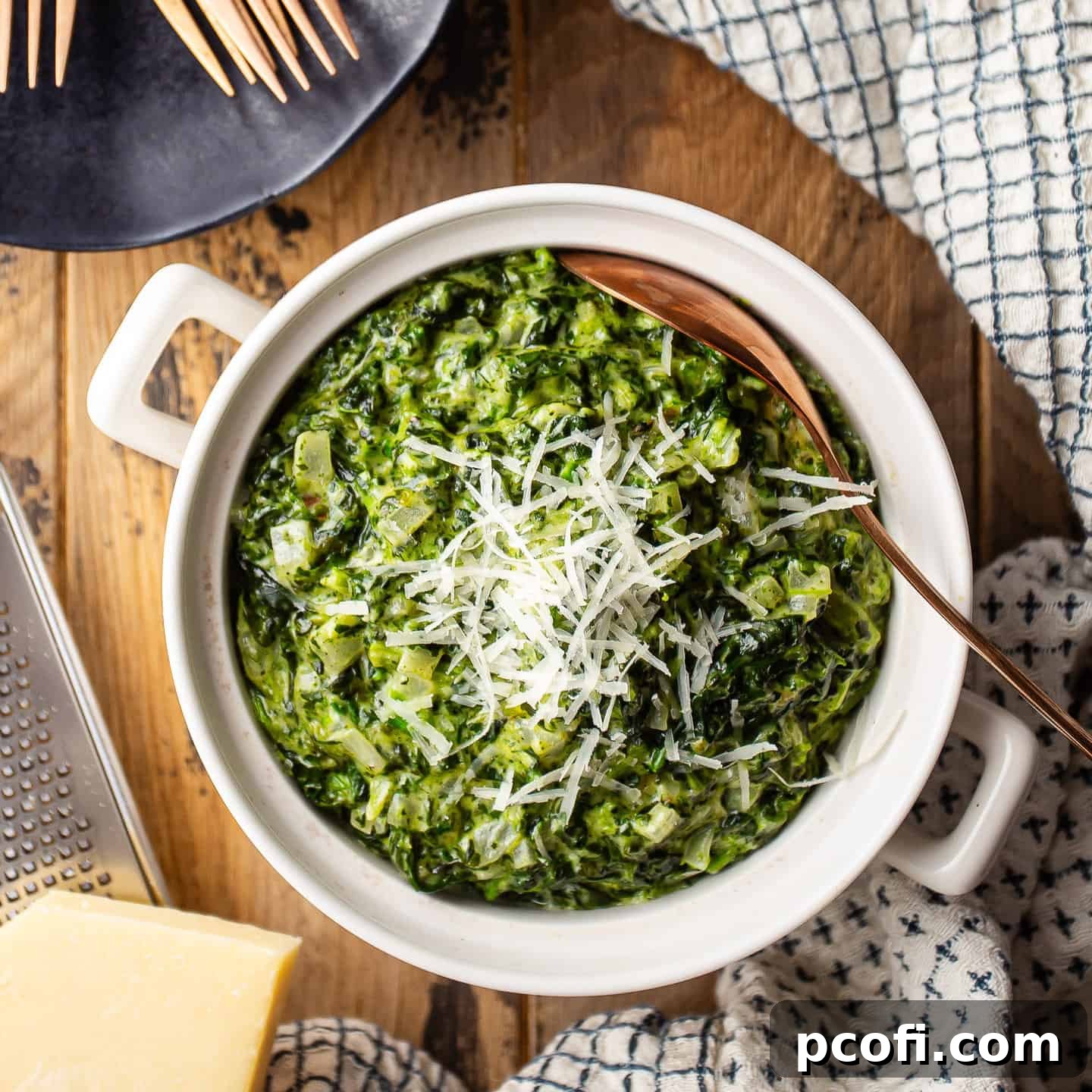 Creamed spinach in a ceramic pot with parmesan cheese.