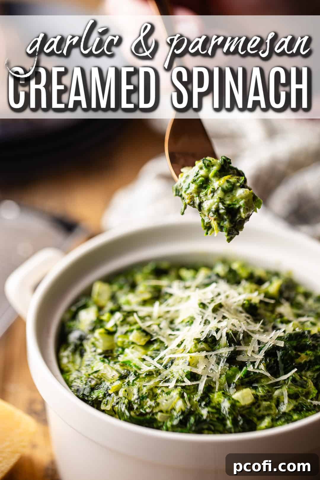 A forkful of creamed spinach being lifted from the serving dish.