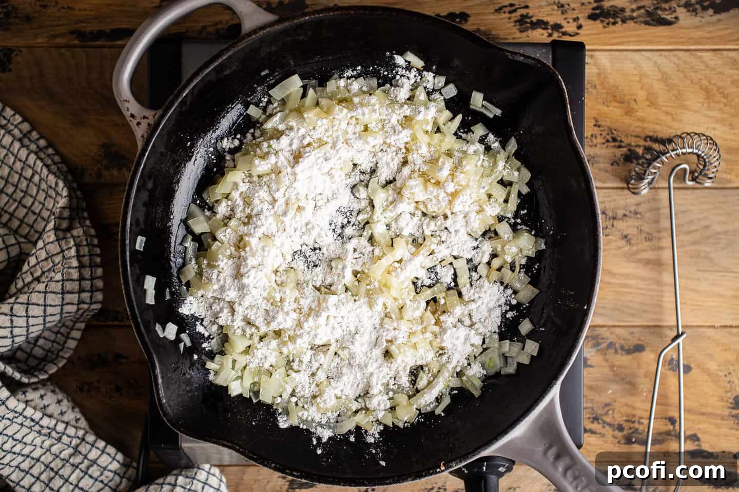 Sprinkling flour over sauteed onions to make a roux.