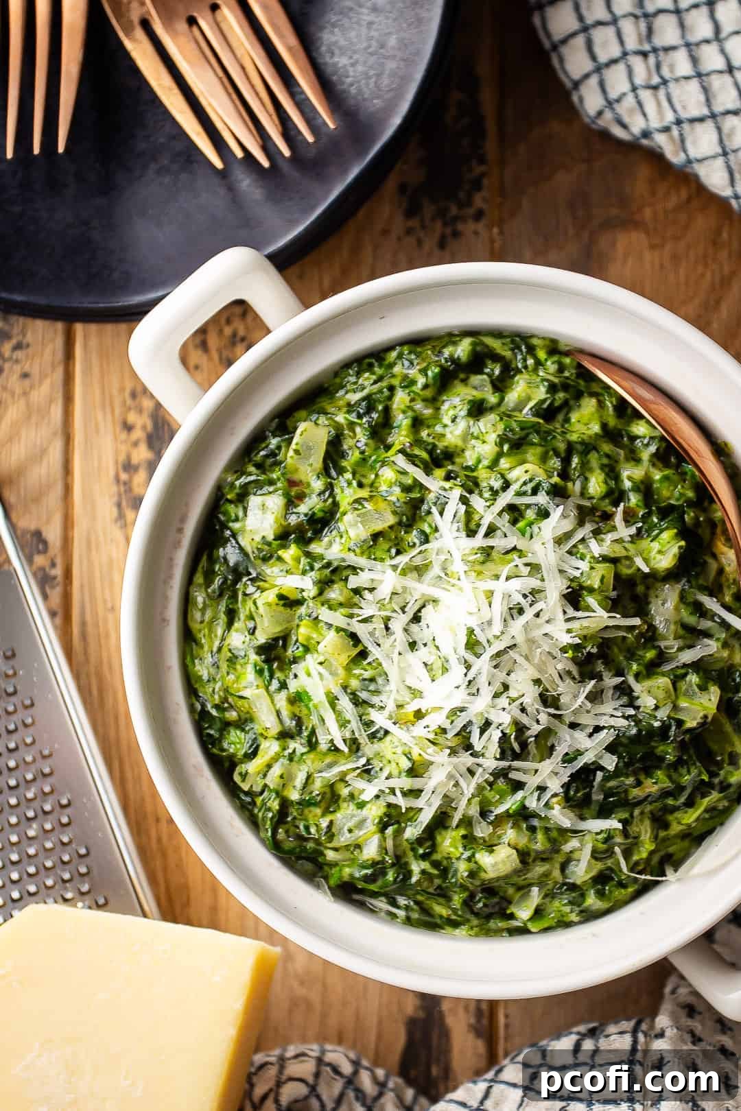 Cream spinach in a small ceramic dish with a copper serving spoon.
