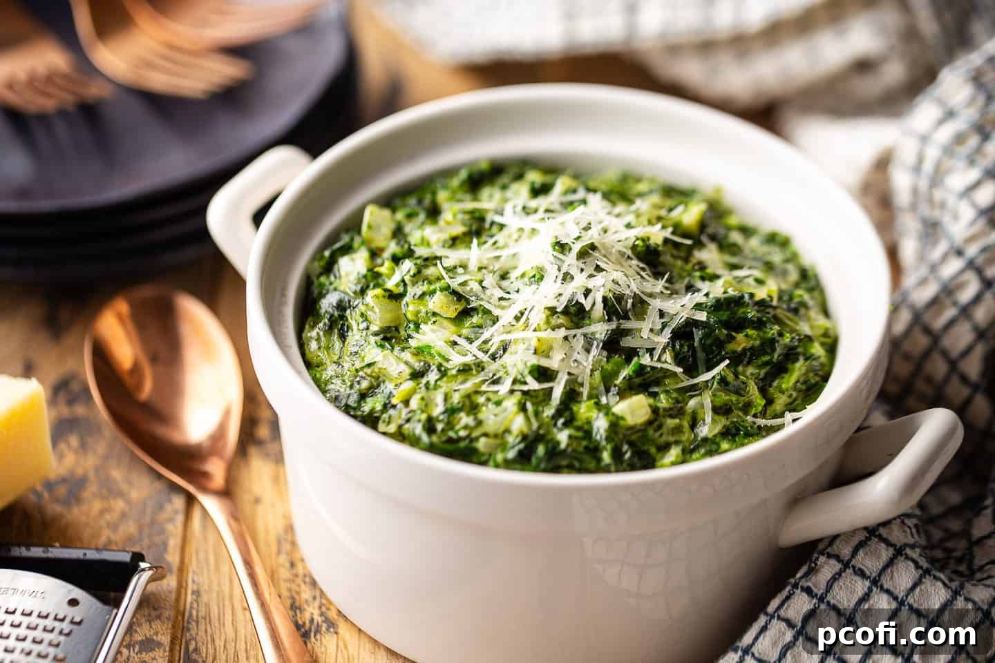 Cream spinach recipe, prepared and presented in a white serving dish with grated parmesan on top.