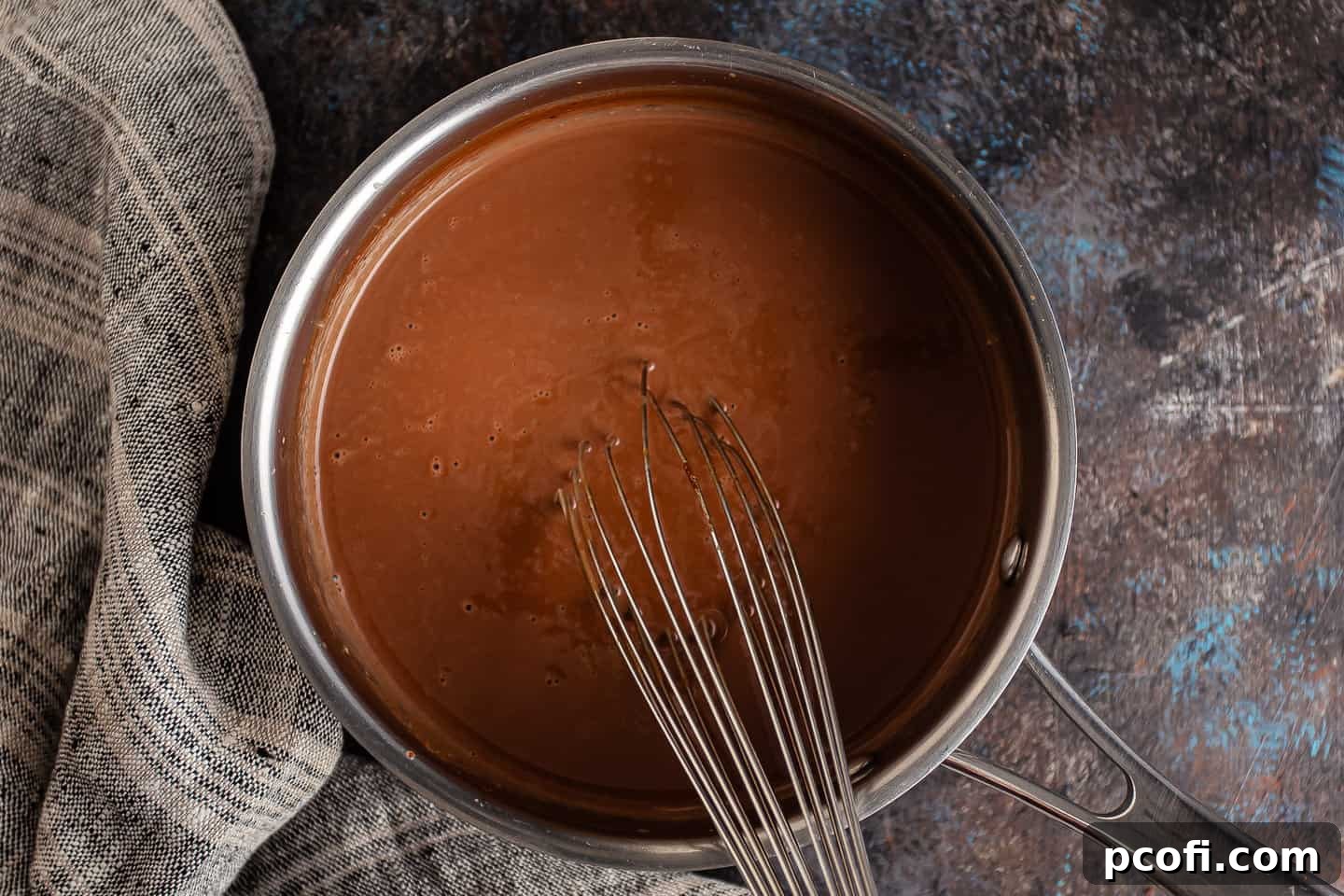Cream and chocolate smoothly melted and blended together in a small pot, forming a rich, uniform chocolate base.