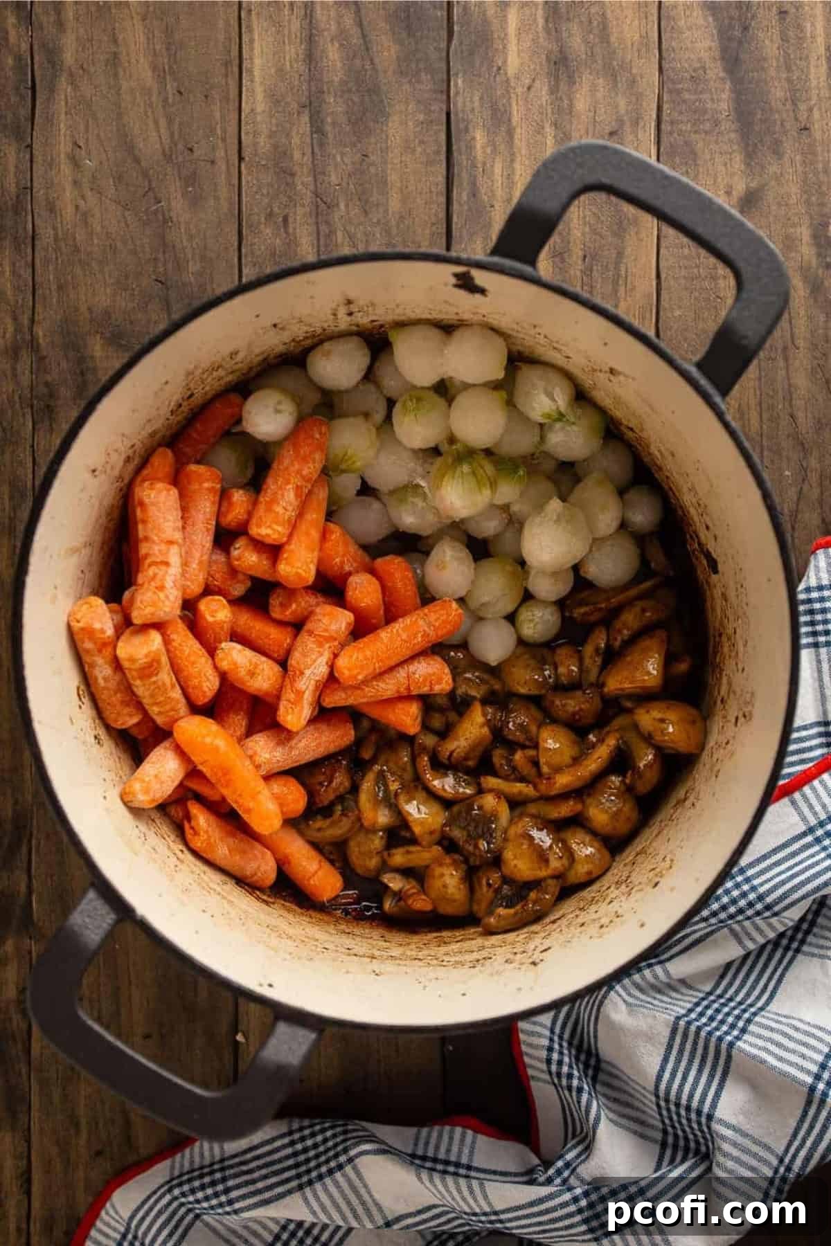 Carrots, onions, and mushrooms sautéing in a pot after the beef has been removed.