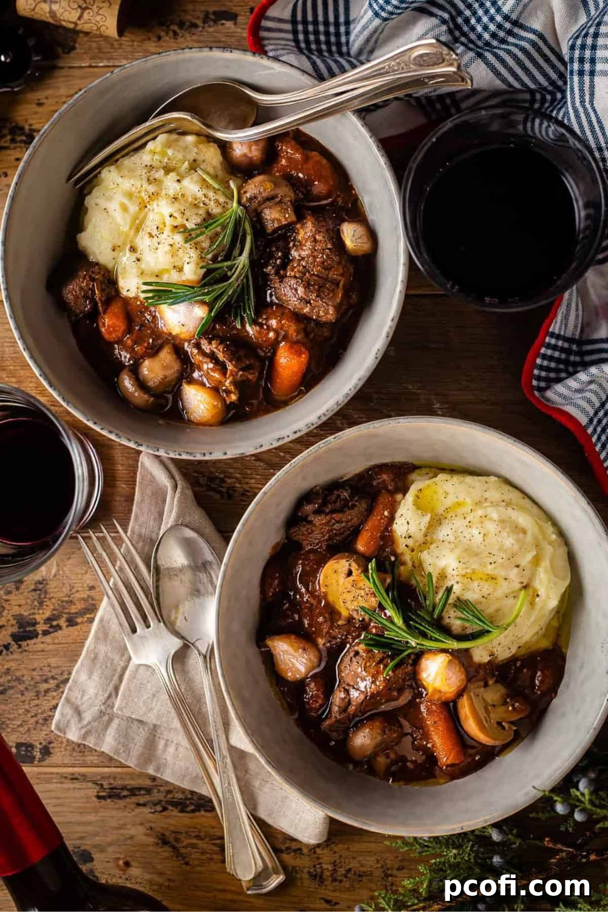 Two elegantly plated bowls of Beef Bourguignon, garnished with fresh rosemary, ready to be served.