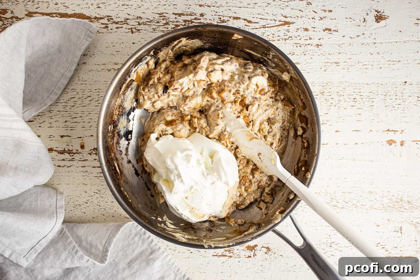 Adding sour cream to French onion dip.