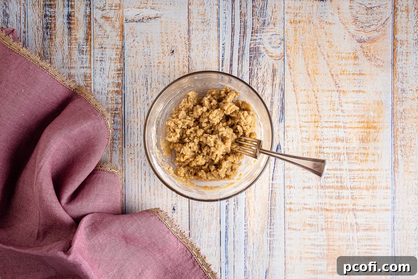 Crumbly streusel topping for raspberry tarts in a glass bowl with a vintage silver fork, ready to be sprinkled.