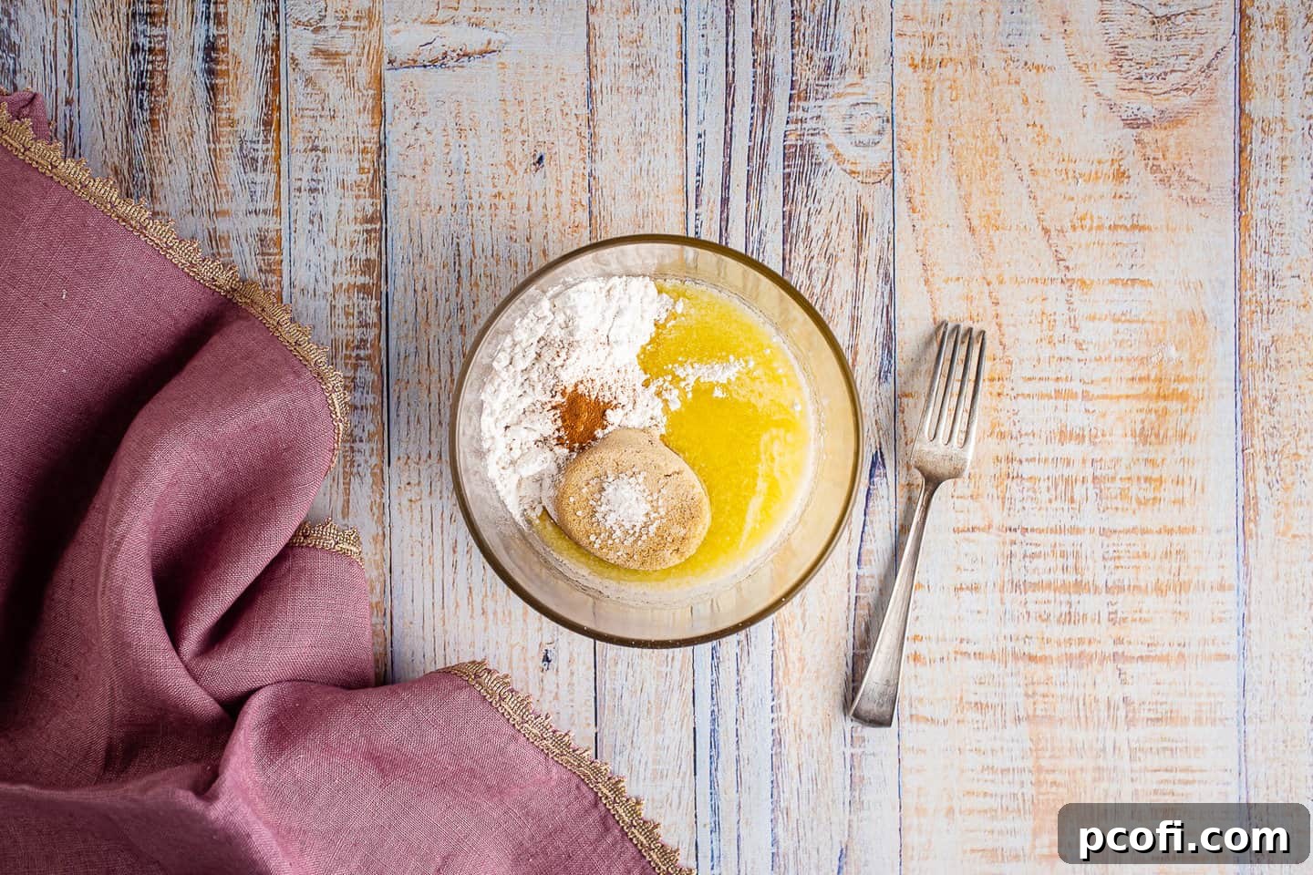 A glass bowl containing ingredients for streusel topping: flour, brown sugar, cinnamon, and salt.