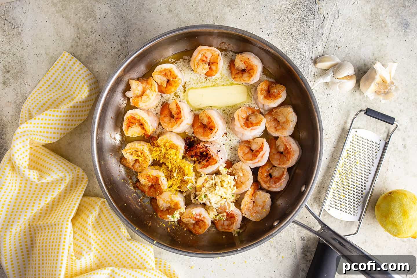 Perfectly seared, golden-brown shrimp sizzling in a large stainless steel skillet, showcasing a delicious crust.