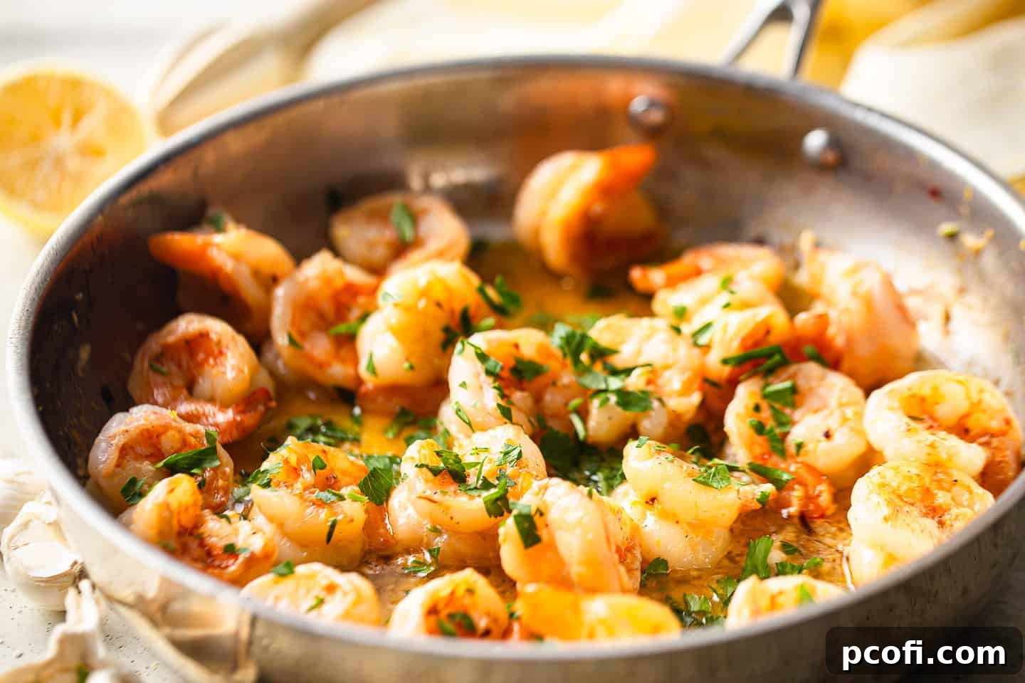 A beautifully presented dish of shrimp scampi with lemon wedges and fresh herbs, highlighting its quick and easy one-pan preparation.