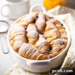 Croissant bread pudding baked in an oval dish with powdered sugar on top.