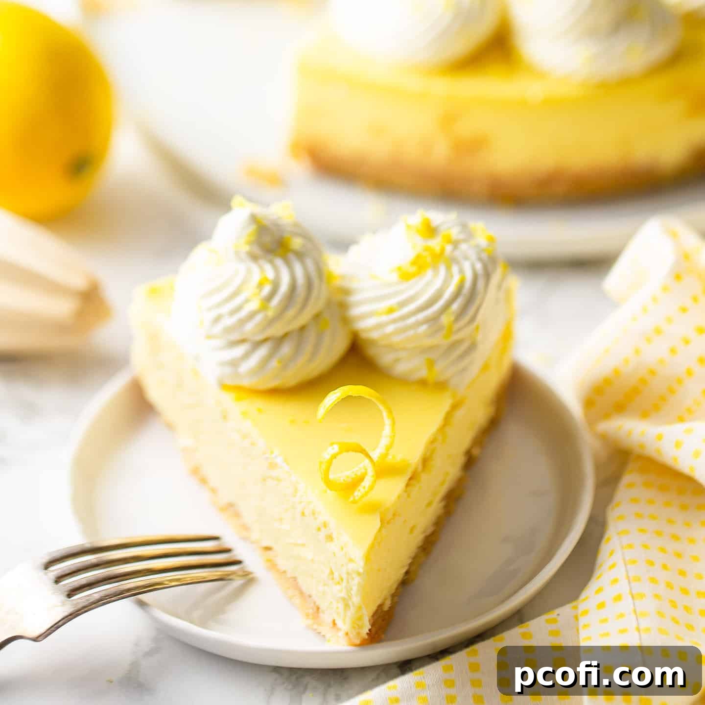A wedge of lemon cheesecake served on a white ceramic plate with a vintage silver fork, highlighting its creamy texture and golden crust.
