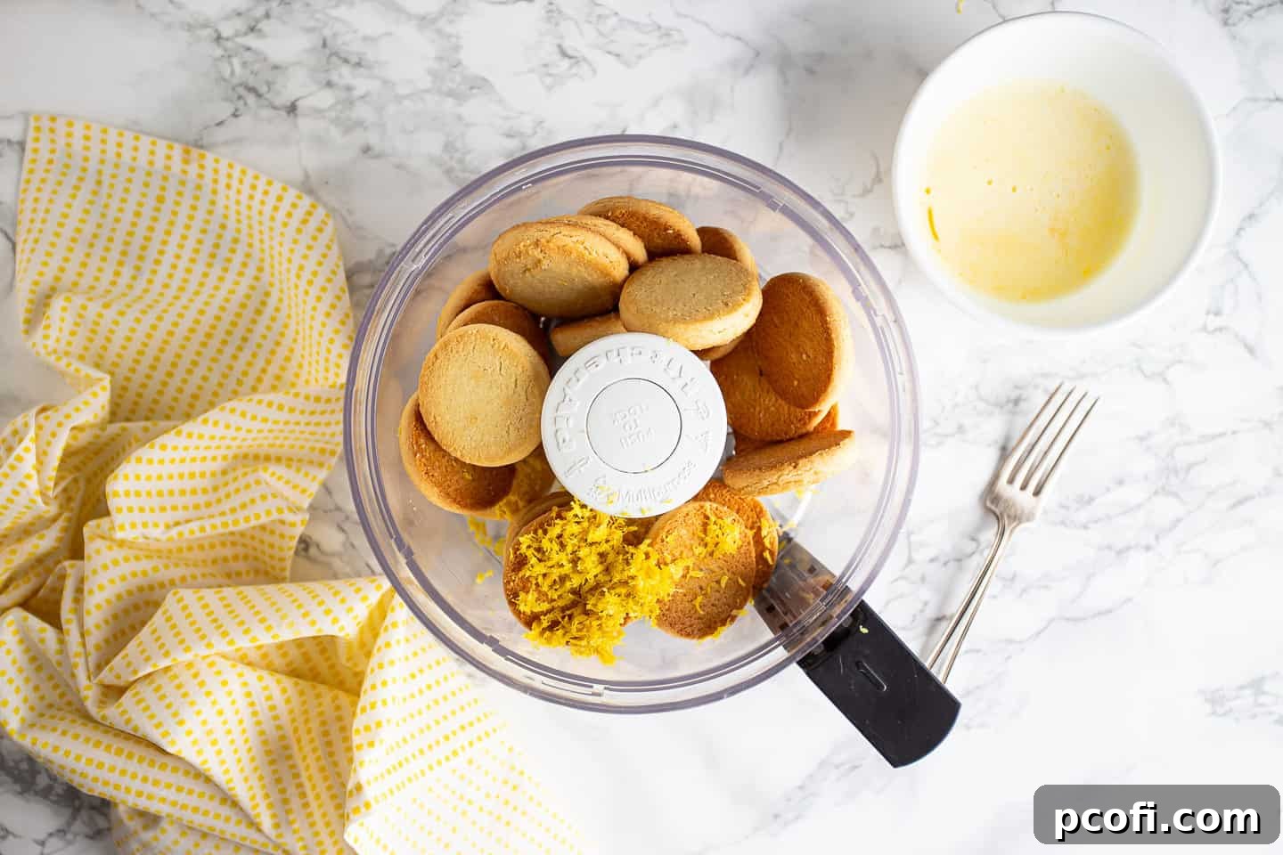 Crushing shortbread cookies and lemon zest in the food processor to create a fine crumb mixture for the cheesecake crust.