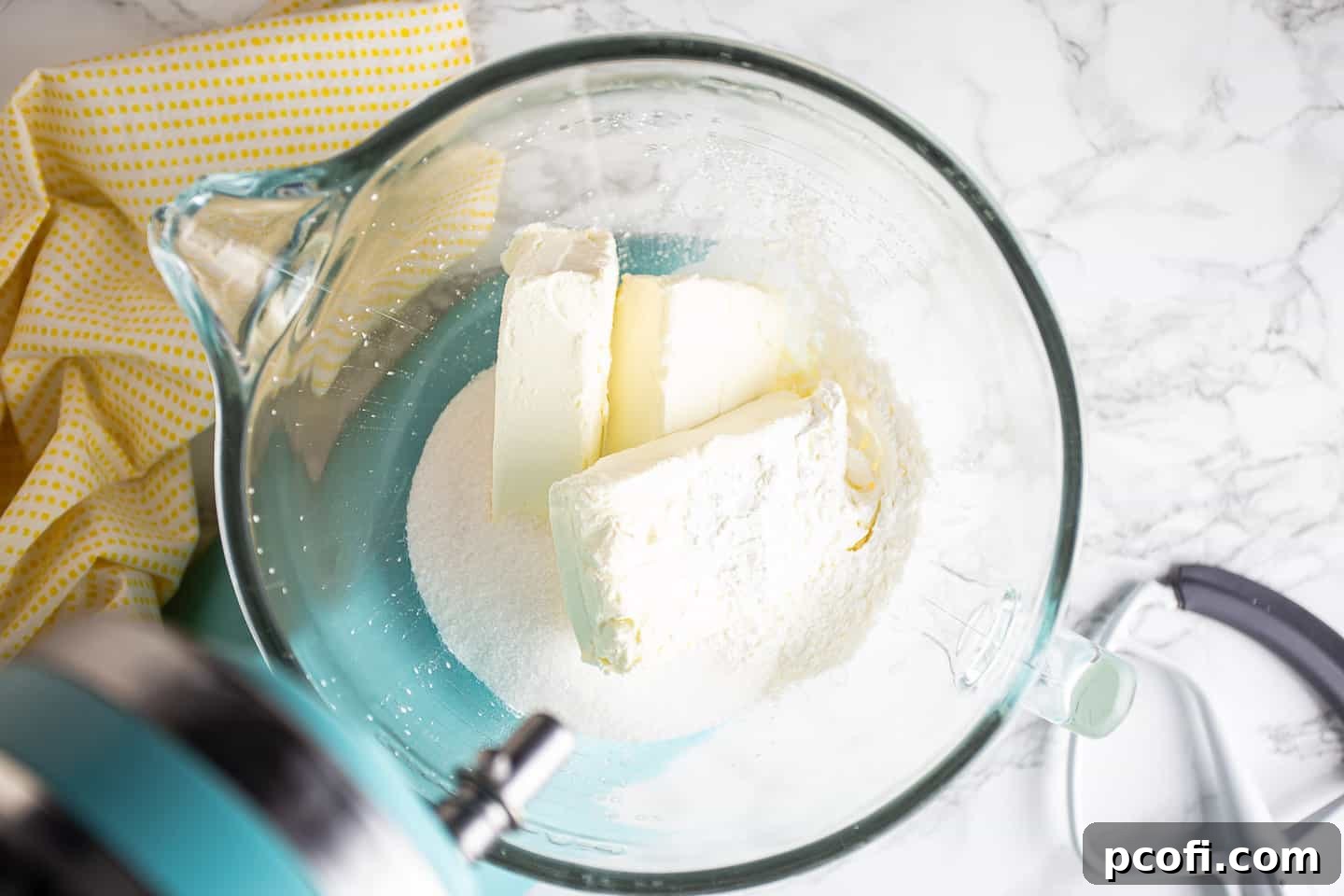 Cream cheese, sugar, cornstarch, and heavy cream in the bowl of a stand mixer, ready to be blended into the cheesecake base.